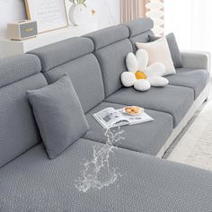 a gray couch with pillows and a white flower on it