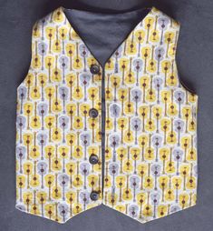 a vest with yellow and grey designs on it, sitting on a gray tablecloth