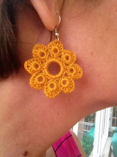 a woman wearing yellow crochet earrings on her back neck, looking at the camera