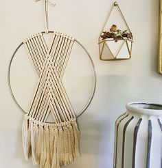 a wall hanging on the side of a white wall next to a vase and other items