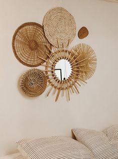 a bed topped with pillows next to a mirror and wall mounted wicker art pieces