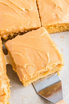 peanut butter frosted cake cut into squares with a spatula