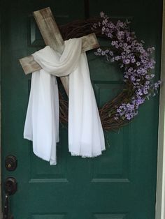 a green door with a cross and white scarf hanging on it's front porch