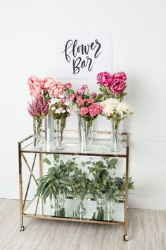 flowers are arranged in vases on a metal stand with a sign above it that says flower bar