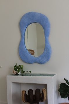 a mirror on the wall next to a table with a vase and potted plant