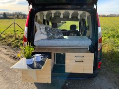 the back end of a van with a bed and drawers on it's side