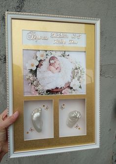 a person holding up a framed photo with baby feet