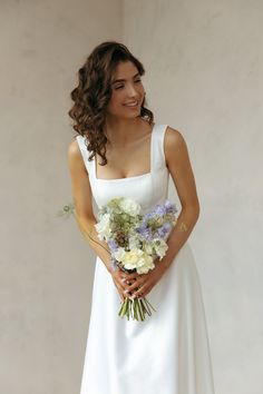 a woman in a white dress holding a bouquet of flowers