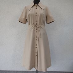 Vintage beige shirtdress in mint condition. Brand R Revija Šibenik Made in Yugoslavia Size 40 (us 10, uk 14) Feels like cotton blend Button front closure Pointy collar  Darts Belt loops and matching belt bust 48 cm = 18.9 inches waist 37 cm = 14.6 inches hips open length 110 cm = 43.3 inches sleeve 28 cm = 11 inches Classic A-line Cotton Shirt Dress, Formal Collared Shirt Dress With Placket, Spring Beige Shirt Dress With Placket, Semi-formal Knee-length Shirt Dress With Placket, Formal Button-up Shirt Dress With Covered Buttons, Beige Button-up Cotton Dress, Khaki Collared Dress For Daywear, Beige Cotton Shirt Dress For Daywear, Collared Beige Cotton Shirt Dress