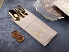 a place setting with two gold forks and one silver fork on top of a napkin