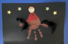 a child's handprint on a black paper with stars and a red cape