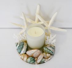 a candle and some seashells on a plate