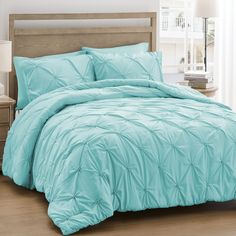 a bed in a room with a light blue comforter and pillows on top of it