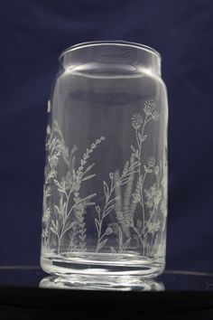 a clear glass vase sitting on top of a black table next to a blue background