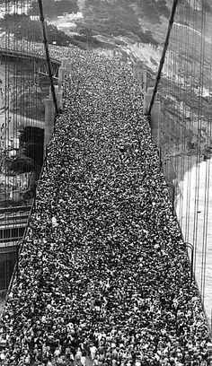 a crowd of people standing on the side of a bridge