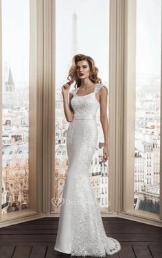 a woman in a white wedding dress standing by a window with the eiffel tower in the background