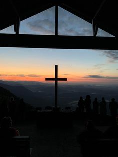 people are gathered at the top of a hill to watch the sun rise over mountains