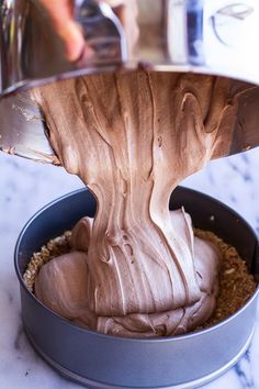 someone is pouring chocolate frosting into a cake pan