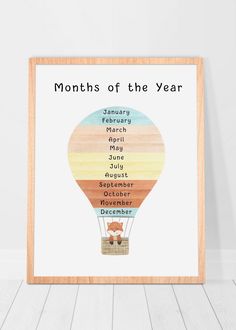 the months of the year print in a wooden frame on a white wall next to a wood floor