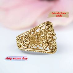 a gold ring sitting on top of a white table next to a pink flower bouquet