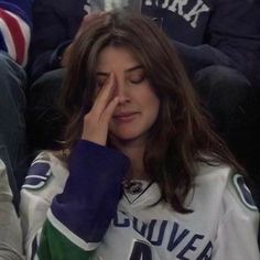 a woman sitting in the stands holding her hand to her face as she looks down