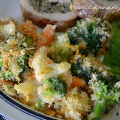 a white plate topped with broccoli, carrots and bread next to a salad