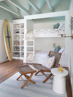 a bedroom with a bunk bed, chair and table in the corner next to a surfboard