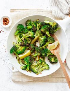 a white bowl filled with pasta and broccoli on top of a wooden table