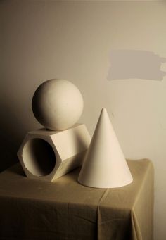 three white vases sitting on top of a table next to a brown cloth covered tablecloth