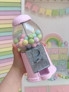 a person holding up a pink gummy machine with lots of balls in it's mouth