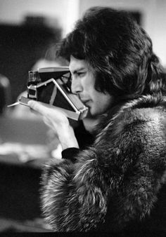 black and white photograph of a man holding a camera in his hand while looking at it