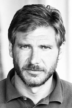 a black and white photo of a man in polo shirt looking at the camera with a serious look on his face