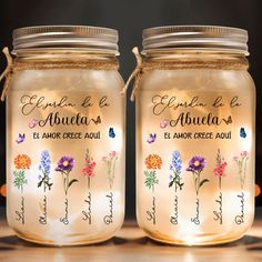 two jars with flowers are sitting on the counter top, one is filled with water and the other has writing in spanish