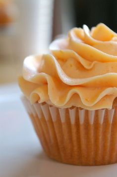 a cupcake with white frosting sitting on top of a table