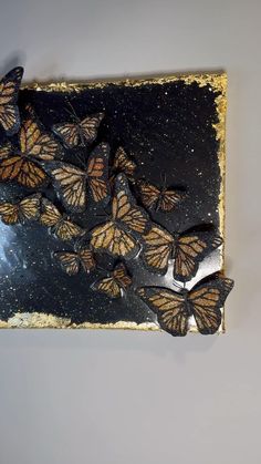 a group of butterflies sitting on top of a piece of black paper with gold flecks