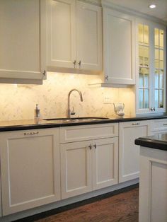 a kitchen with white cabinets and black counter tops