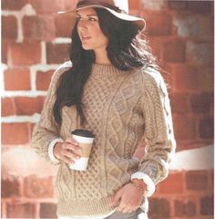 a woman in a hat and sweater holding a coffee cup