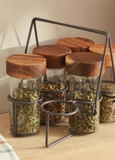 four spice jars with wooden lids on a shelf