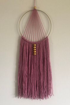 a pink wall hanging on the side of a white wall with a circular metal frame