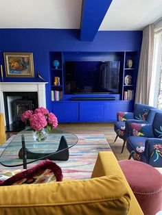 the living room is painted bright blue and has flowers in a vase on the coffee table