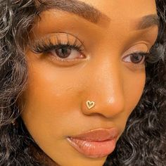 a close up of a woman with a nose piercing on her nose and curly hair