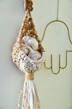 there is a hanging basket with sea shells in it and a hook on the wall