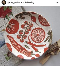 a red and white plate sitting on top of a table next to two wooden utensils