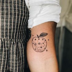 an apple tattoo with stars on the inside of its arm and behind it is a black outline