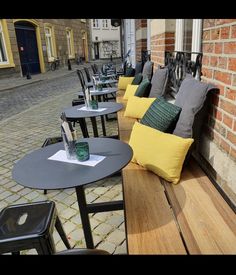 tables and chairs are lined up on the side walk in front of a brick building