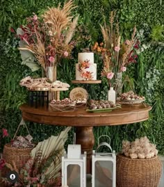 a table topped with lots of desserts next to a wall covered in greenery