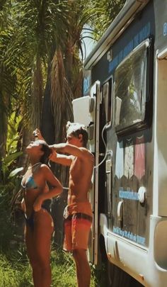 a man and woman standing in front of a van with towels hanging out to dry them