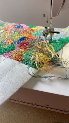 the sewing machine is working on some colorful thread spools that have been sewn together