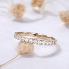 an image of two wedding rings on top of a white table with flowers in the background