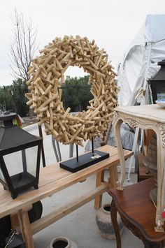 a wooden table topped with a wreath next to a lamp and other items on top of it